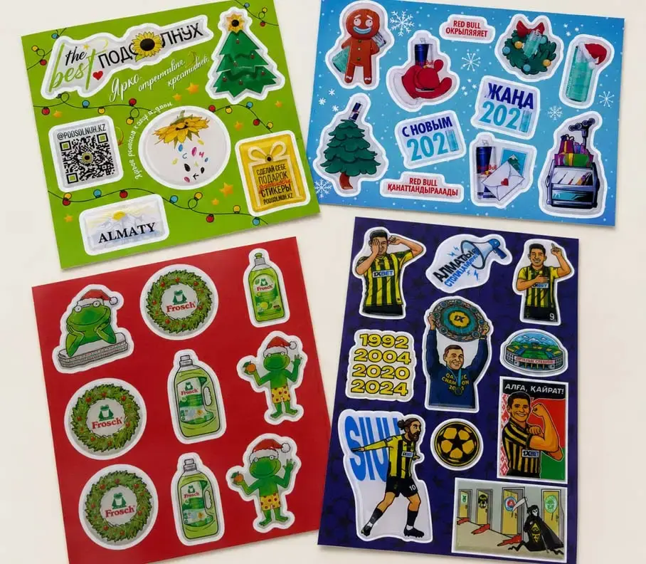 Four printed sheets of domed stickers with seasonal and football designs, laid out on a table