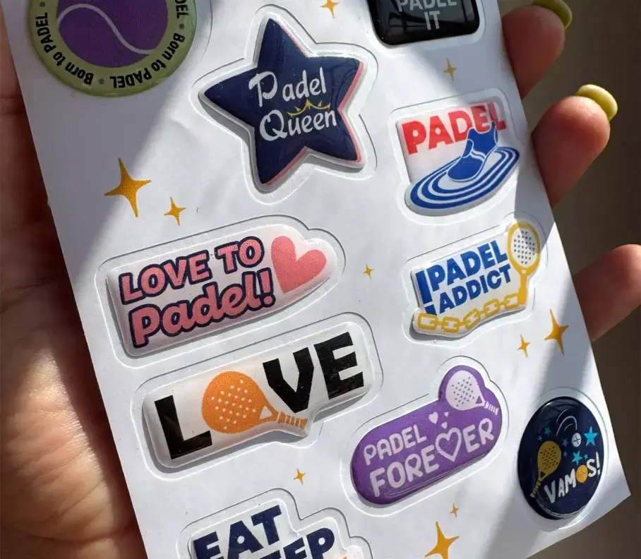 Sheet of die-cut domed stickers on a padel-tennis theme, held in the hand