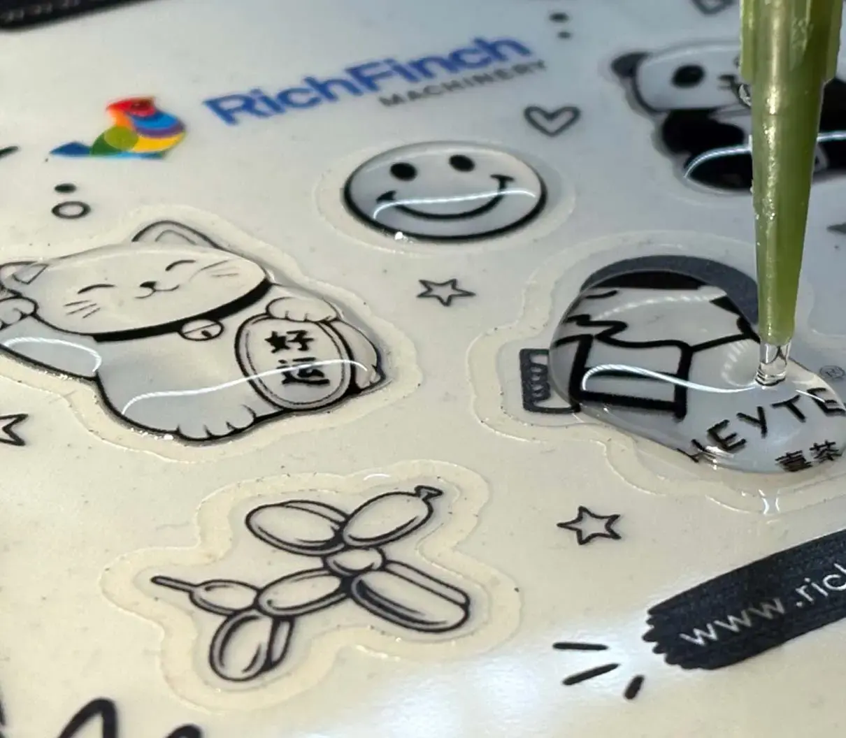 Dispensing needle laying resin onto a sticker on a sample sheet, finished domes around it