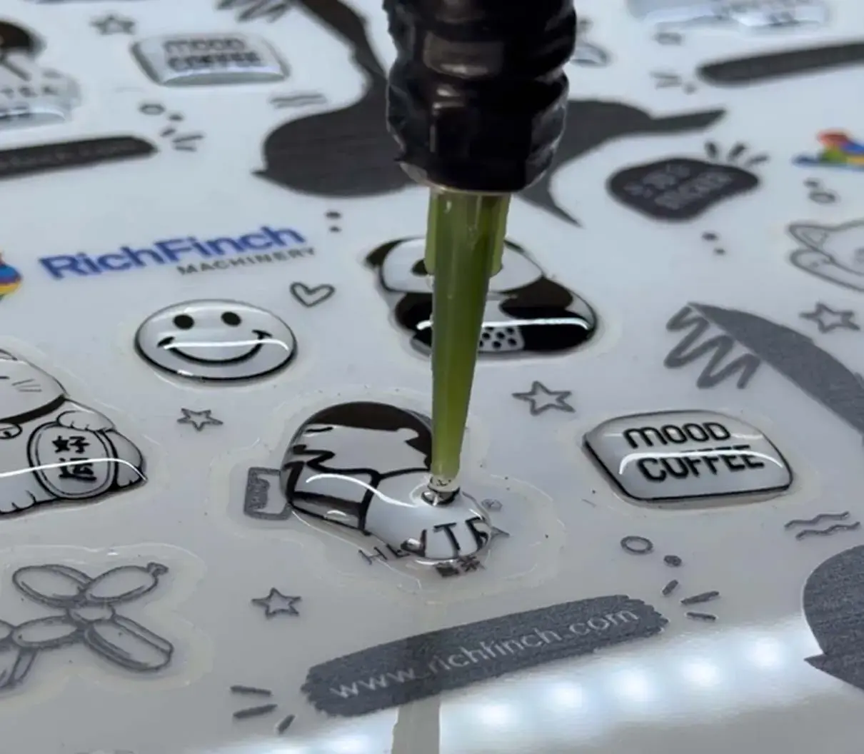 Dispensing head laying polyurethane resin onto a printed sheet, photographed close